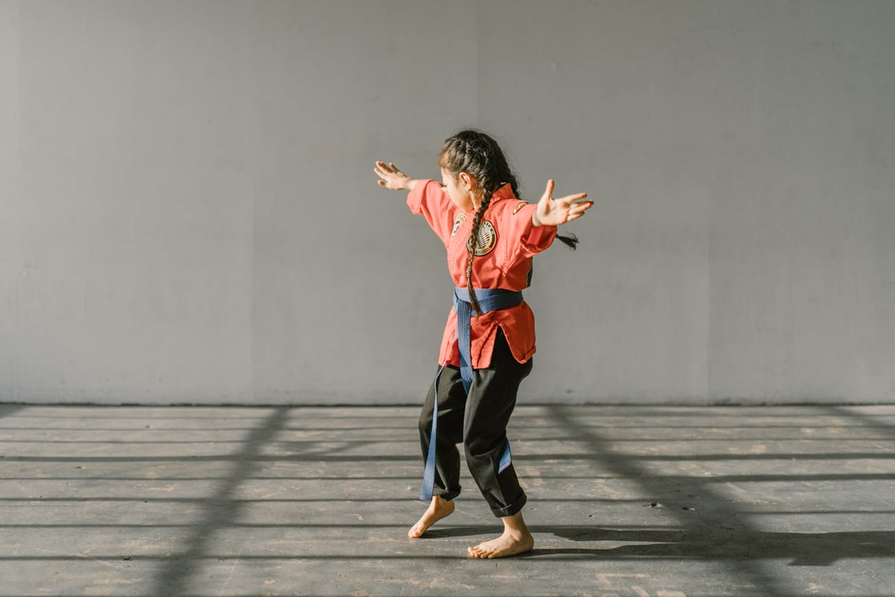 A young martial artist in uniform practicing indoors with focus and energy.